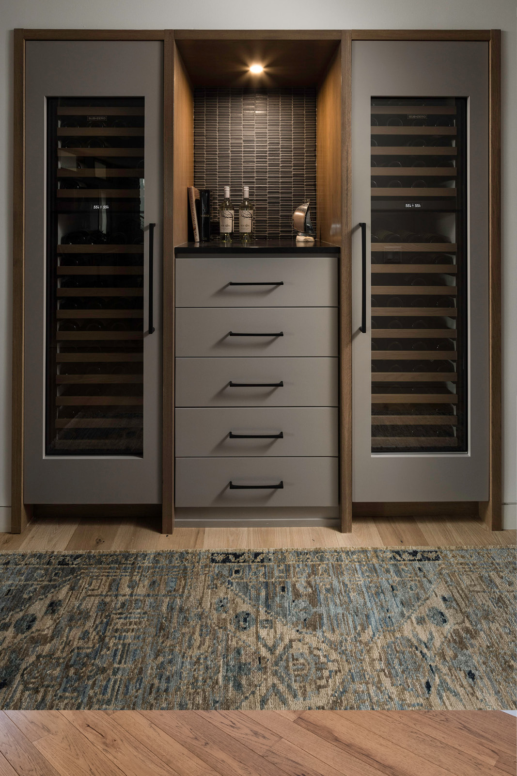 Wine storage room at Grasshopper Hill in Elkhart Lake Wisconsin featuring custom cabinetry, wine cooler and detailed tile backsplash