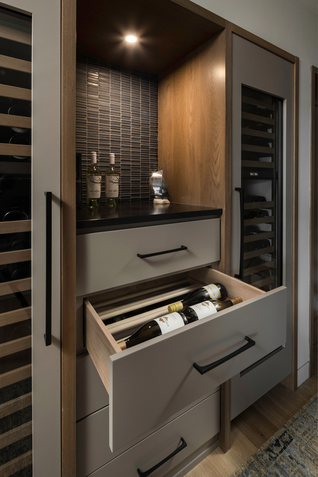 Wine storage room at Grasshopper Hill in Elkhart Lake Wisconsin featuring custom cabinetry, wine cooler and detailed tile backsplash