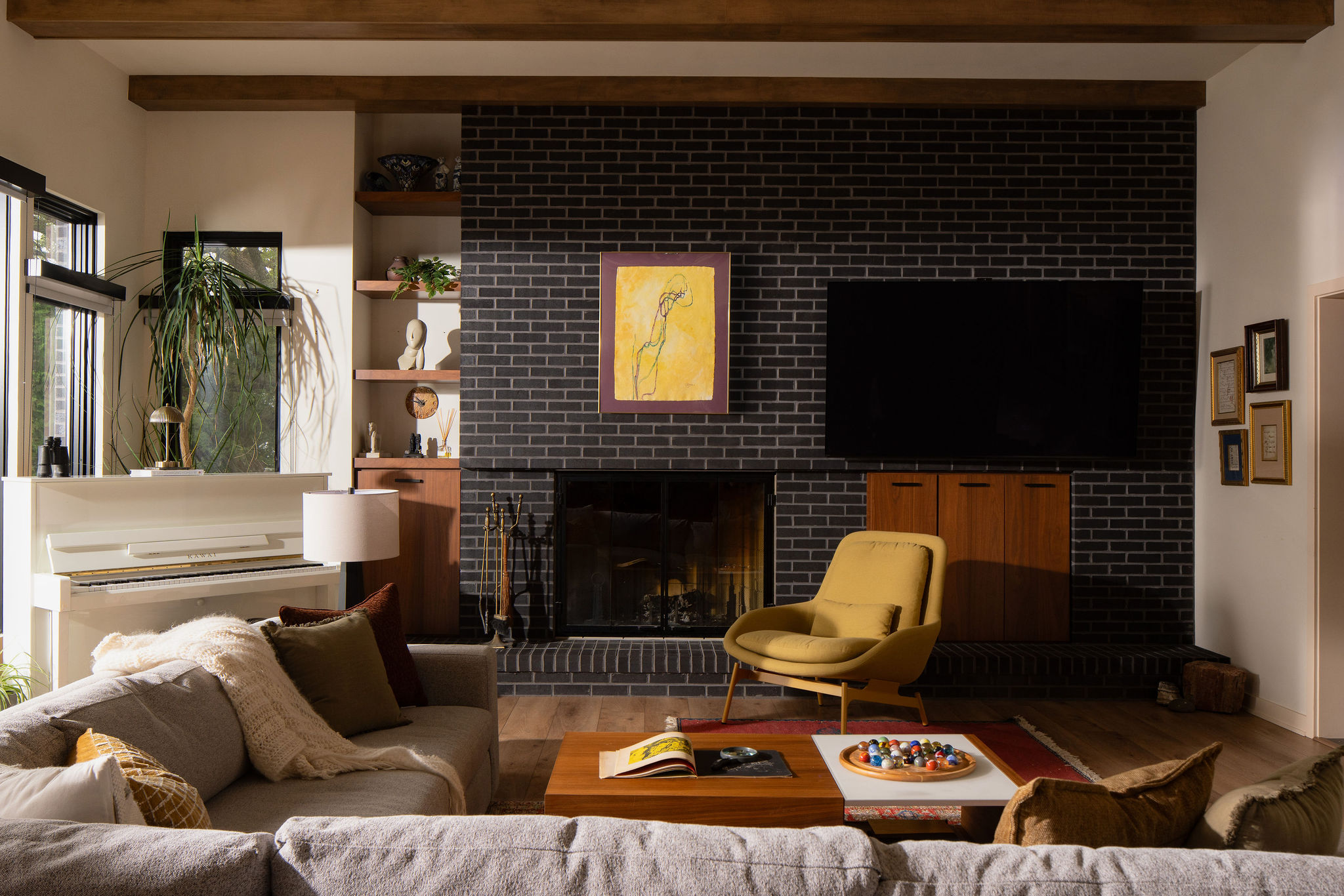 The MCM Lake House – Living Room Mid-century modern living room with black brick fireplace, walnut cabinetry and Lake Michigan views