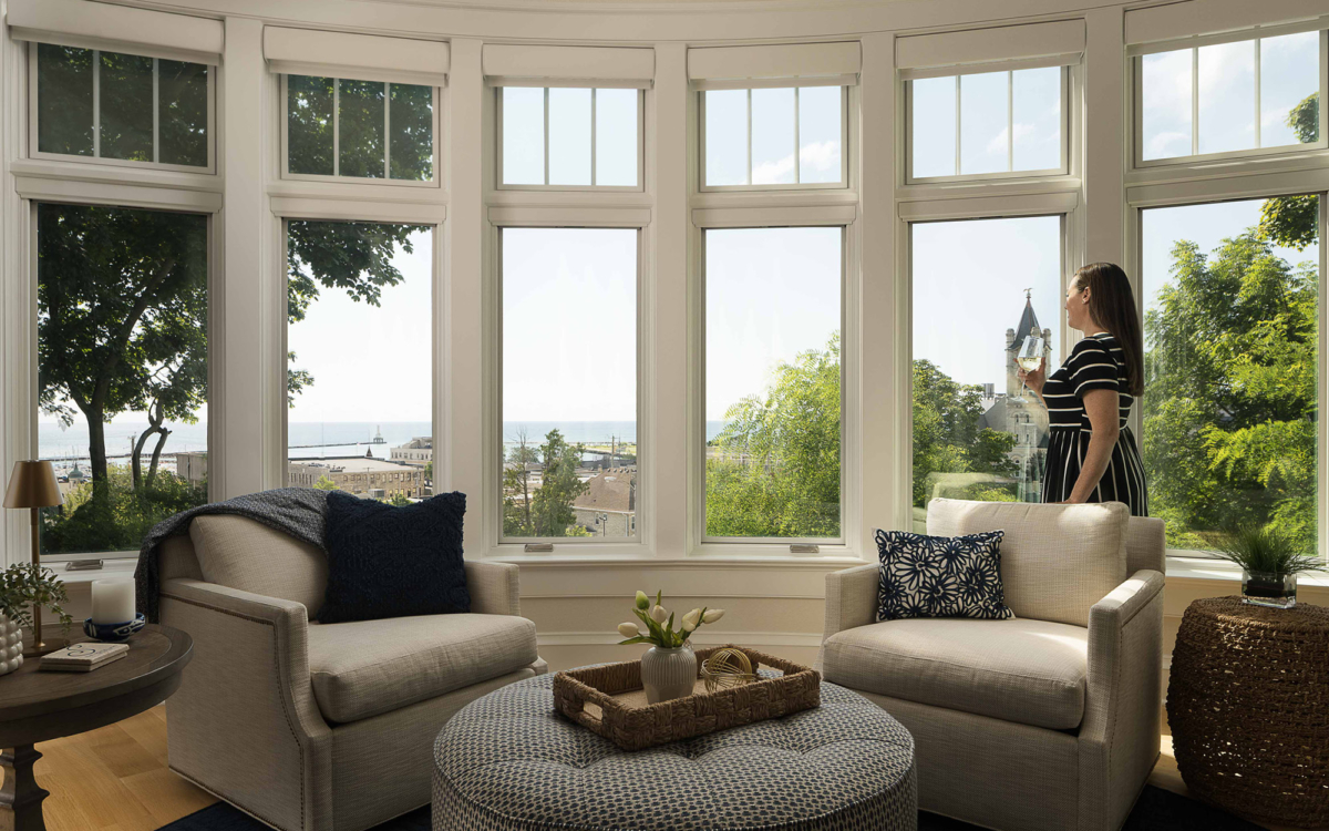 Lake Michigan custom home design with a sitting area of cream armchairs beneath a wall of windows